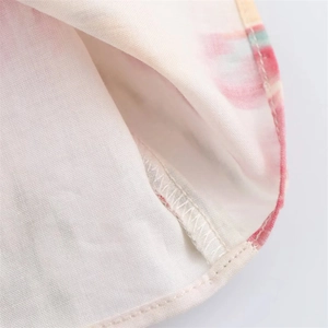 Macro shot of cotton linen fabric detail with pink watercolor print and neat hem stitching