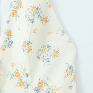 Macro detail of poplin floral print featuring soft yellow and blue blossoms on cream fabric