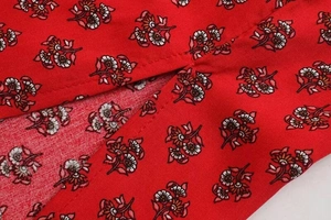 Macro detail of sewing craftsmanship and vintage floral print on red cotton dress fabric
