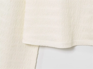 Vue détaillée du tissu blanc texturé ondulé montrant les plis et les coutures