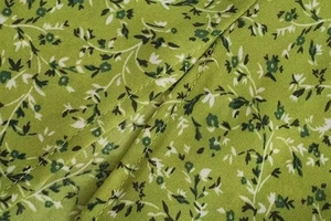 Close-up of green floral chiffon fabric with fine stitching and vine patterns