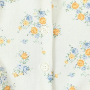 Close-up of floral print poplin fabric with white buttons on beige spring dress