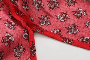 Close-up of high-quality stitching and floral print pattern on red cotton dress fabric