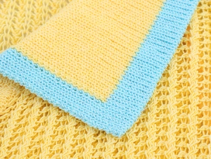 Détail de tissu en maille jaune et bleu clair montrant la texture ajourée et respirante
