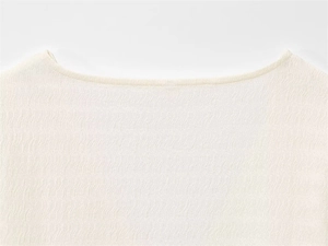 Détail de la texture du tissu plissé blanc et de la couture de l'encolure pour hauts femme