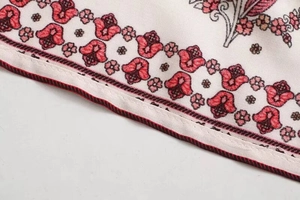 Close-up of exotic floral print fabric and fine stitching detail on summer dress hem