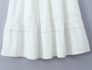 Detailed view of the white skirt hem with delicate hollow lace and wave pleated texture