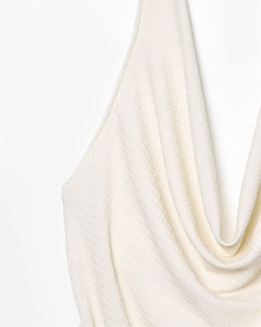 Detailed close-up of white halter top featuring textured fabric and draped pleated neckline