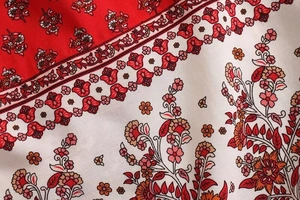Macro detail of bohemian floral print fabric with red and beige block patterns