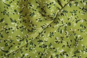 Close-up of green floral chiffon fabric texture with delicate white leaf patterns