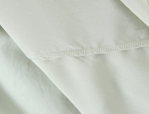Gros plan sur la couture overlock et la texture tissée d'une robe vert menthe