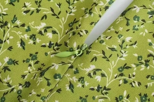 Detail view of the green floral chiffon dress showing the seamless invisible zipper and fabric texture