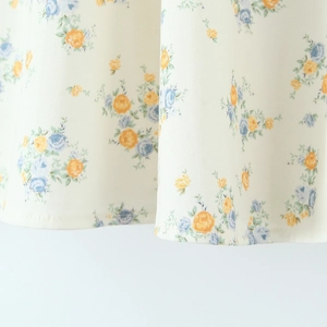 Close-up of floral print poplin fabric in blue and orange on a cream base dress