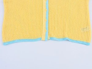 Détail de la texture maille ajourée avec bordure contrastée et boutons jaunes assortis