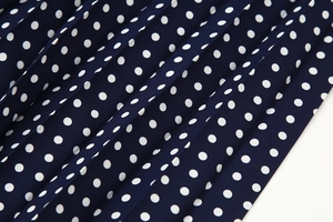Close-up of navy blue polka dot pleated fabric showing fine texture and accordion folds