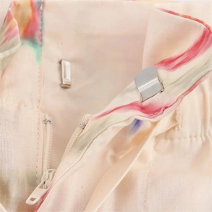 Detailed macro shot of the metal hook closure and zipper on abstract floral printed pants