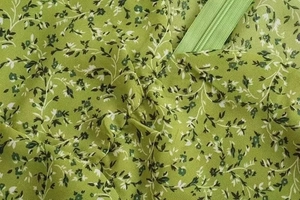 Detail of green floral fabric featuring ruched texture and a hidden nylon zipper closure