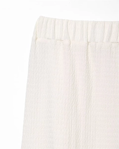 Close-up of white elastic waistband and vertical wavy pleated texture on women's casual pants