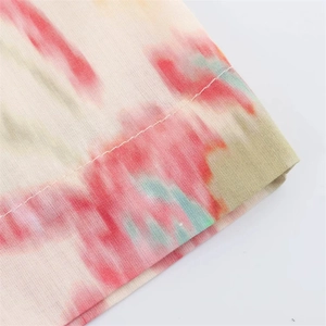 Macro detail of soft tie-dye knit fabric showing pink green watercolor print and stitching