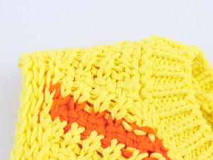 Dettaglio ravvicinato del tessuto a maglia giallo con motivi geometrici arancioni