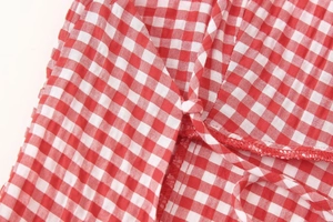 Detailed macro view of red and white gingham fabric with crinkle texture and neat stitching