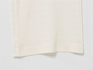 Détail macro du tissu blanc avec texture ondulée et coutures de qualité du pantalon