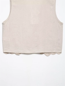 Close-up of beige linen blend vest featuring intricate eyelet embroidery and scalloped hem