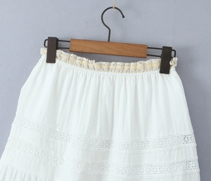 Detail of white midi skirt featuring textured fabric and intricate floral lace embroidery