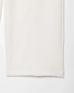 Detail of seersucker textured fabric showing premium hem stitching on an off-white top