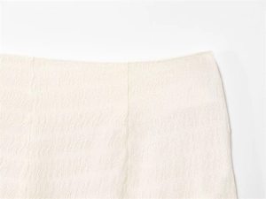 Gros plan sur un tissu ivoire texturé à vagues avec coutures verticales pour pantalon