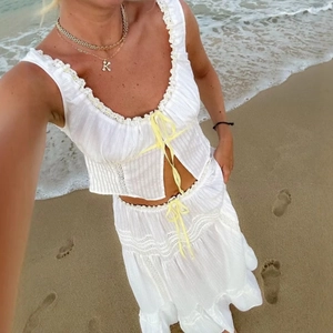 Detail of bohemian white two-piece set with yellow ribbon ties and lace ruffles