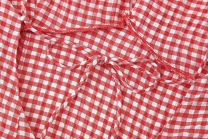 Detail of red gingham dress showing tie-up straps and high-quality overlock stitching