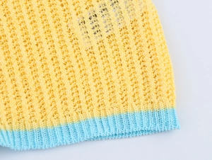 Détail du haut polo en tricot crocheté jaune avec bordure côtelée bleu clair tissée
