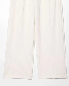 Detailed close-up showing the textured waffle fabric and clean hem of white wide-leg trousers
