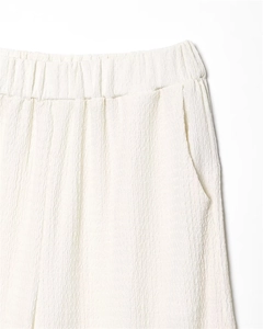 Close-up of elastic waistband and pleated fabric texture on off-white casual pants