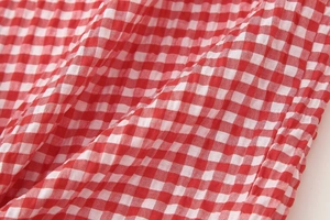 Detailed close-up of red and white gingham seersucker fabric texture for summer dress