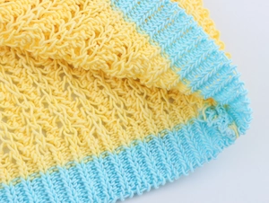 Vue macro d'un tricot jaune ajouré avec bord-côte bleu et texture douce respirante