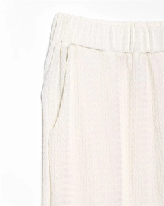 Close-up of off-white elastic waist trousers showing detailed seersucker fabric texture