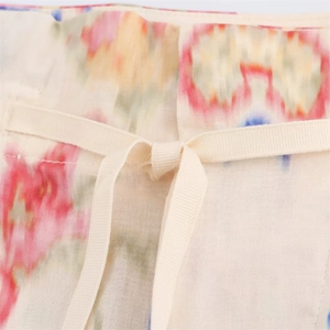 Close-up of artistic floral print waist detail and woven drawstring on cream fabric