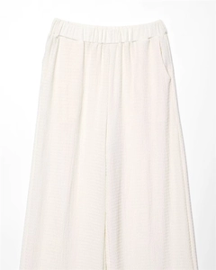 Detail of cream high-waist wide-leg trousers with elastic waistband and textured fabric