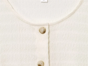 Détail d'un haut blanc en seersucker avec boutons marbrés et tissu crêpe texturé