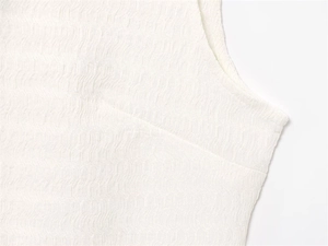 Détail du tissu seersucker blanc avec des coutures précises et une texture plissée ondulée