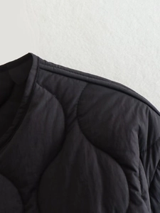 Detail of black wave-quilted jacket featuring a round neckline and premium stitching