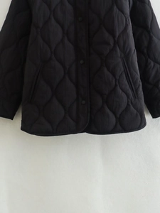 Detailed view of black quilted jacket with snap buttons and water drop wave stitching