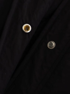 Detailed close-up of metal snap buttons on black side-slit cotton jacket for women