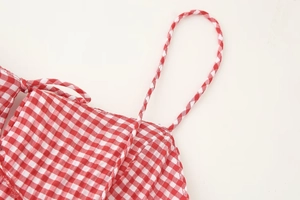 Detail of red gingham seersucker fabric texture and delicate spaghetti strap sewing