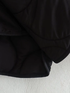 Close-up of black wave-quilted jacket hem with refined edge detailing and warm texture