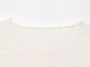 Détail du tissu gaufré blanc texturé sur un ensemble de loisirs boutonné pour femmes