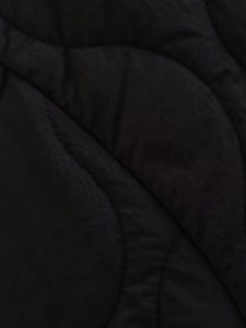 Detail view of black quilted fabric with elegant wave stitching for women's winter coats