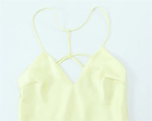 Detail of light yellow satin dress showing delicate V-neckline and thin cross straps
